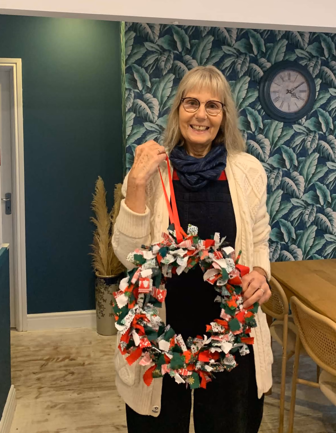 Helen Shakespeare holding a Christmas rag wreath made from strips of red, green and white fabric